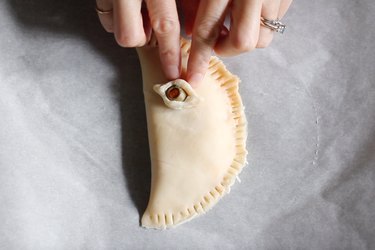 Pressing eye-shaped olive onto calzone