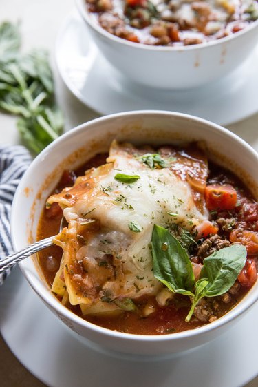 Two bowls of lasagna soup with cheese on top