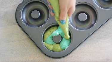 Piping green and blue donut batter into pan