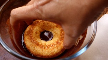 Dipping healthy coconut flour low carb donuts in chocolate coating.