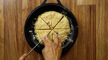 Cutting a round of low-carb, gluten-free scone dough into 8 wedges.