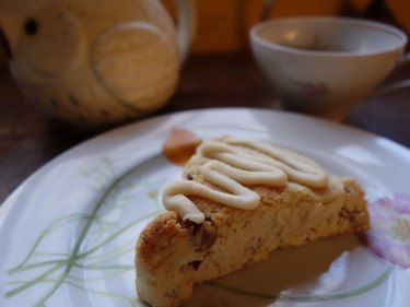 Gluten free low carb maple pecan scone on a plate with teacup in background.