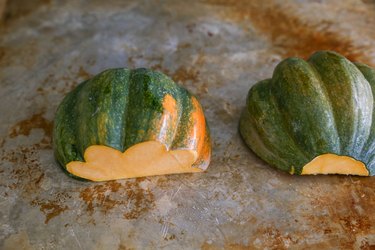 acorn squash face-down on a baking sheet