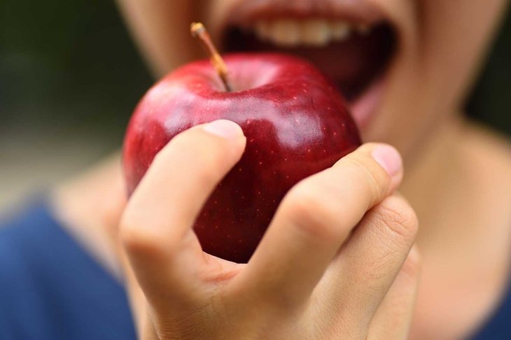 The woman holding fresh apple to eating